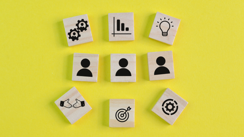 Blocos de madeira com ícones representando fatores importantes antes de contratar um CRM. Título: Fatores essenciais na escolha de um CRM.